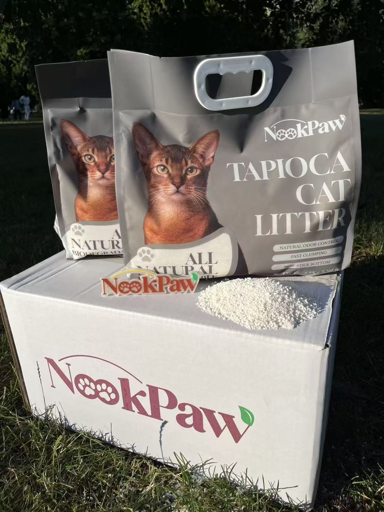 Two NookPaw Tapioca Cat Litter bags displayed outdoors with natural tapioca granules